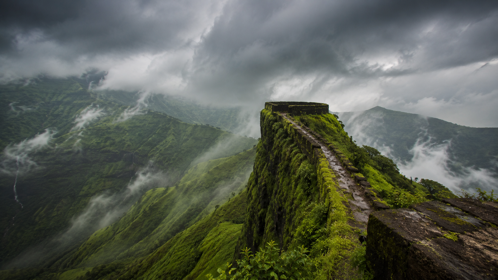 The Vinchu Kata spur at Lohagad Fort with monsoon clouds rolling over the ramparts