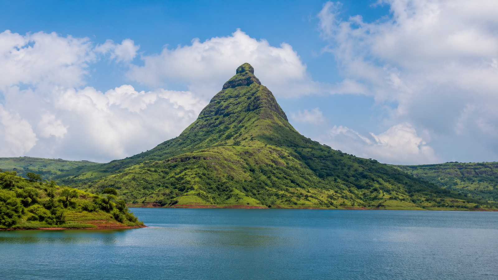 The triangular profile of Tikona Fort rising above Pawna Lake