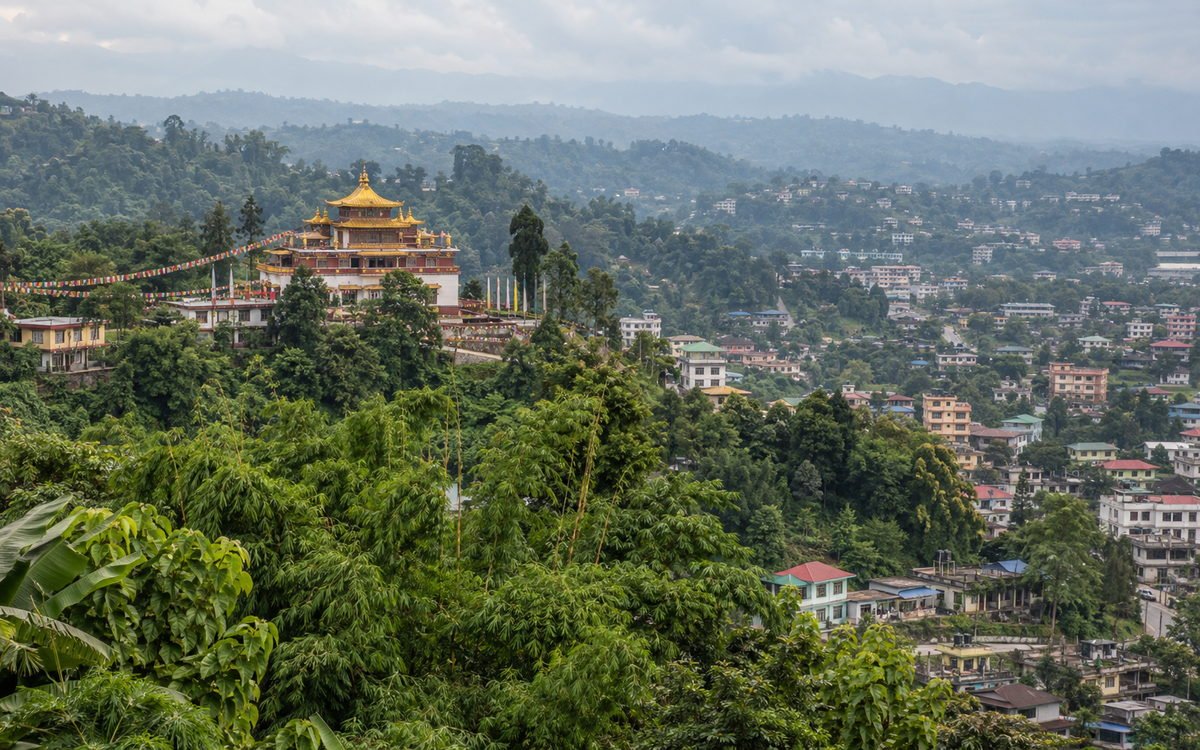 Green Himalayan foothills around Itanagar, Arunachal Pradesh, with a Buddhist gompa among forested slopes