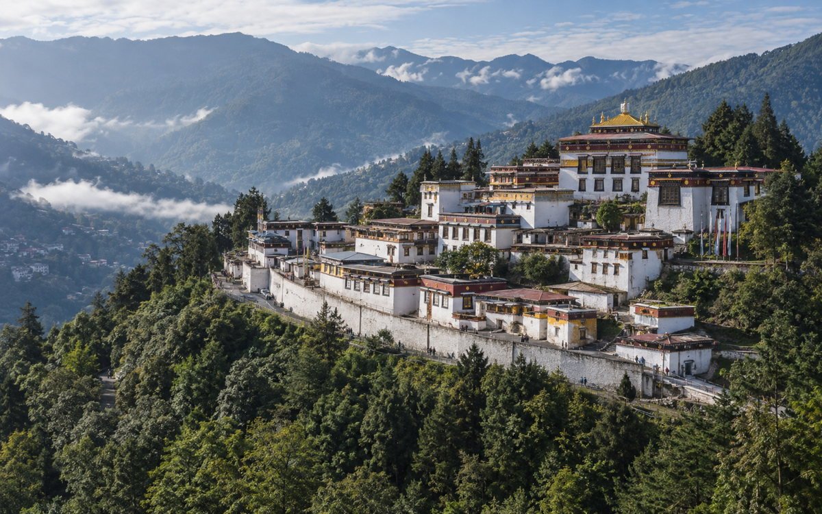 Tawang Monastery's white walls and golden roof above a forested Himalayan valley in western Arunachal Pradesh