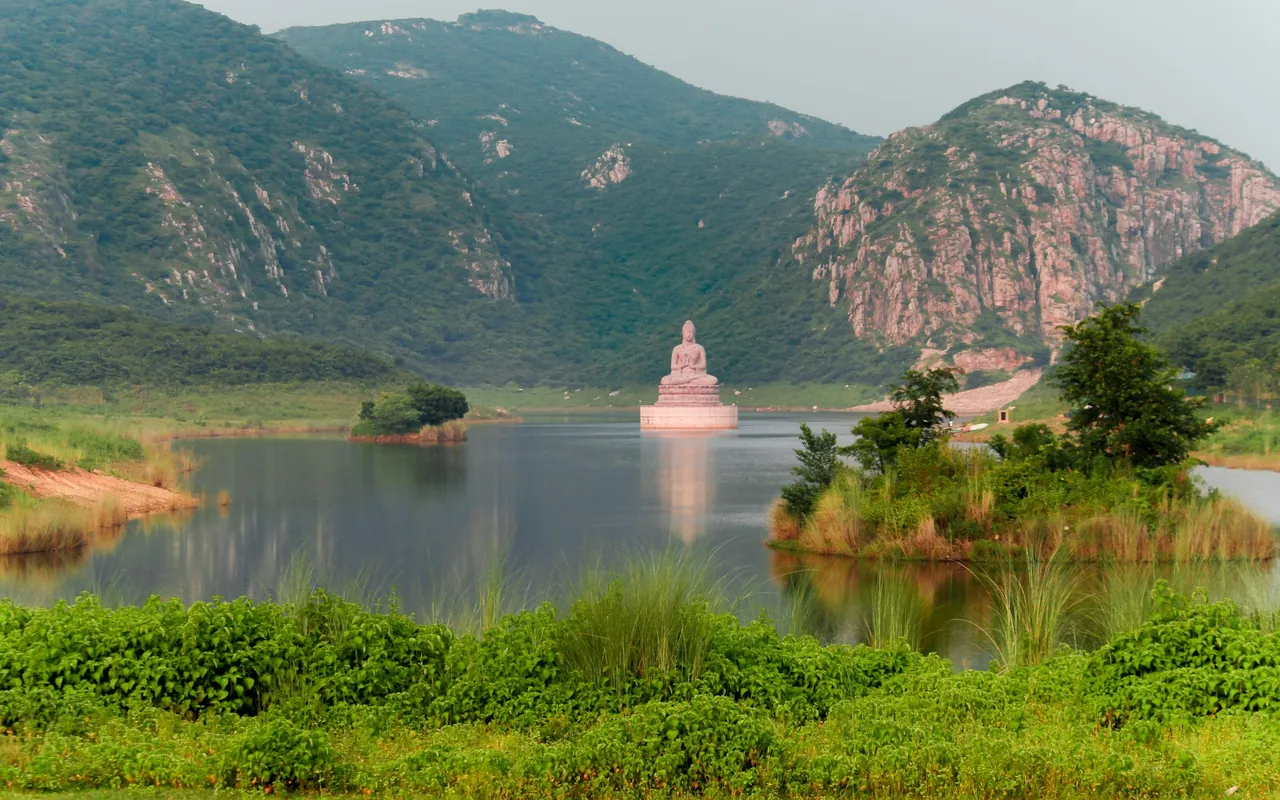 A Buddha statue on an island in Ghora Katora Lake, ringed by the Rajgir hills, Bihar