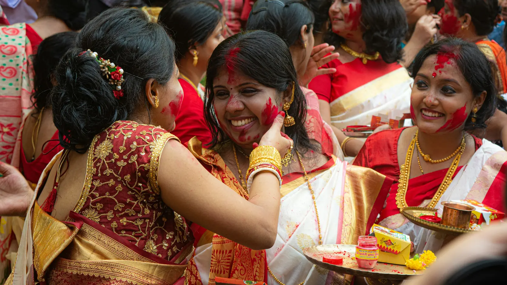 Women in red-and-white saris smearing vermilion on each other during sindoor khela at Bagbazar, Kolkata