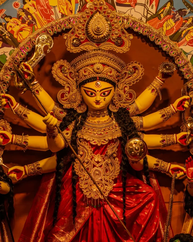 Ten-armed Durga idol in red and gold, crowned and garlanded, at a Kolkata Durga Puja pandal