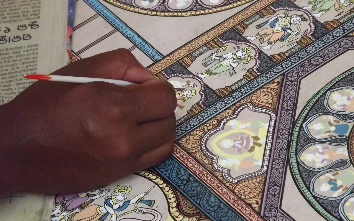 A pattachitra artist painting fine detail on cloth in Raghurajpur, Odisha