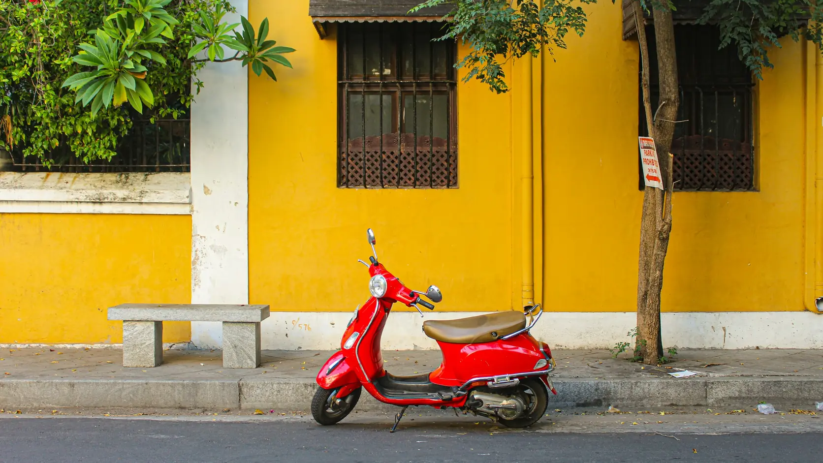 A red scooter parked beside a mustard-yellow wall in White Town, Pondicherry