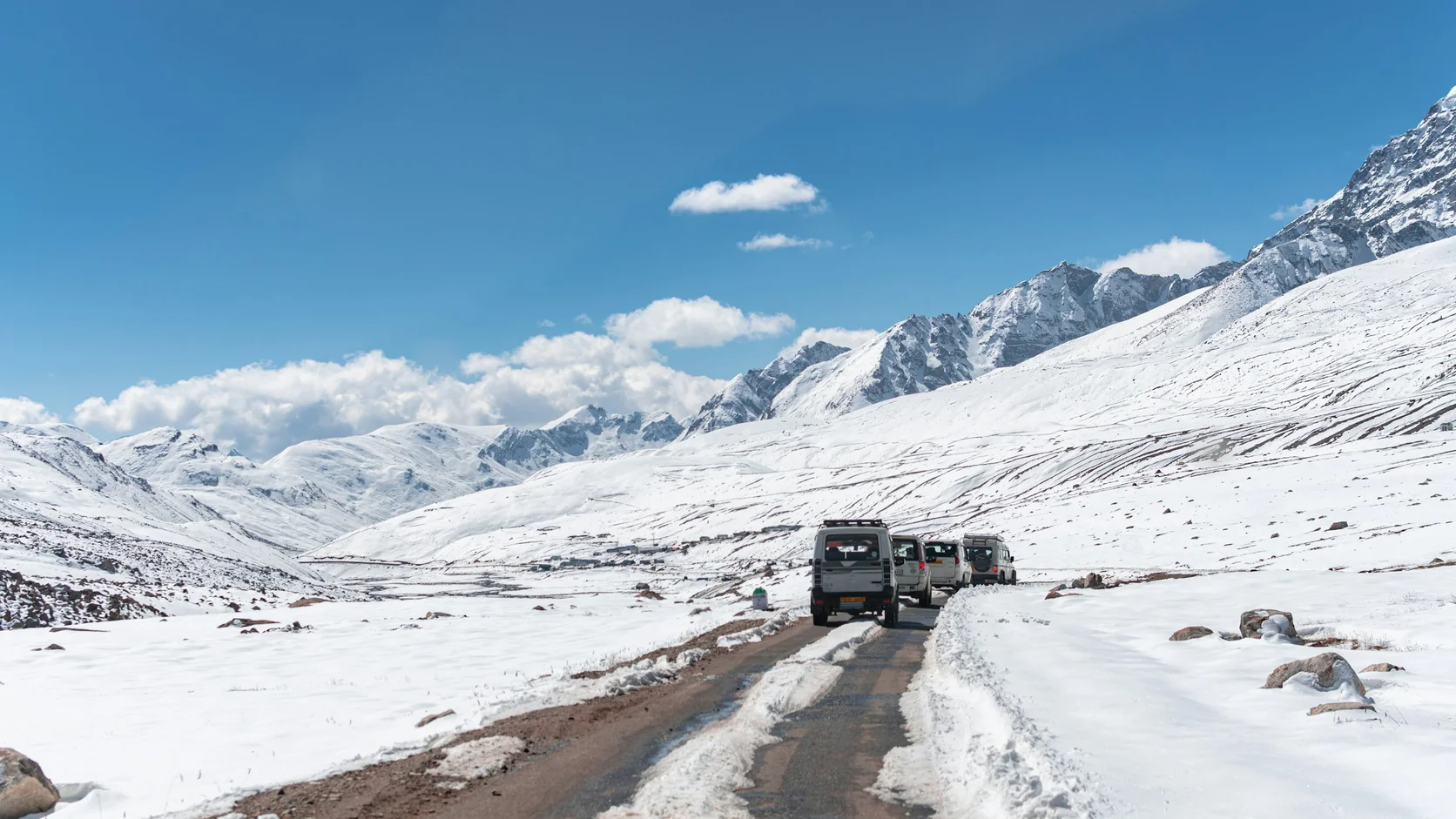 A convoy of jeeps on a snow-lined high-altitude road in North Sikkim